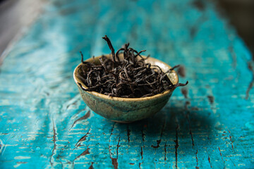 Beautiful and traditional envrionment of old wooden table and Chinese black tea on tea cup and some leaves spread on the table