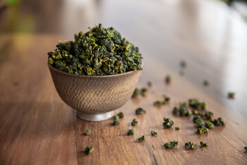 Beautiful and traditional envrionment of old wooden table and Chinese green tea on tea cup and some leaves spread on the table