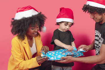 united family opening a christmas present on a pink background