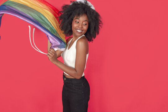 young black woman smiling with an LGBT flag standing