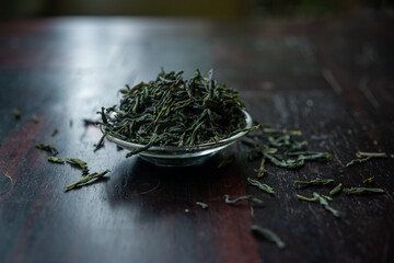 Beautiful and traditional envrionment of old wooden table and Chinese green tea on glass cup and some leaves spread on the table