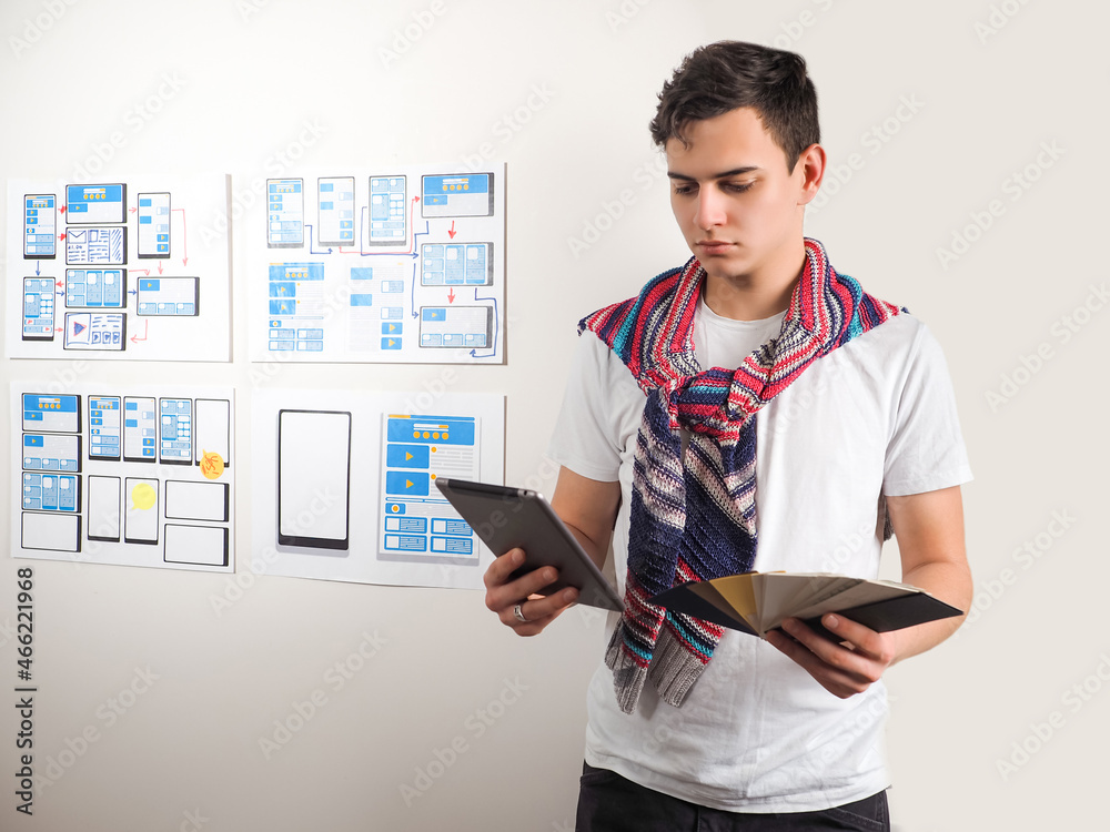 Poster ux dessinger with a tablet in hand. he holds a palette of colors his hands. man designer chooses a c