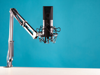 Obraz premium Professional studio condenser microphone. Microphone for recording music. It is secured to a black tripod. A device for recording audio compositions. Studio microphone on a blue background.