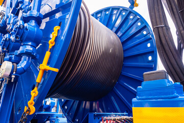 Hose or electrical cable is coiled around giant spool. Concept production of electrical cables....