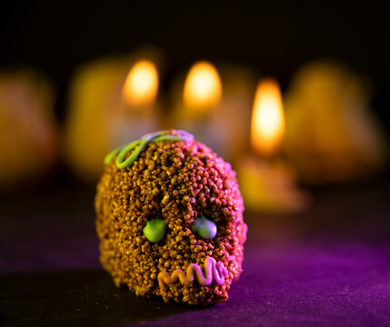 calaverita de amaranto con chocolate tradicional de d&iacute;a de muertos y velas desenfocadas