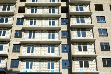 New building. Construction of an apartment building in Moscow. Residential house in sunlight. Inserted plastic windows in the house.