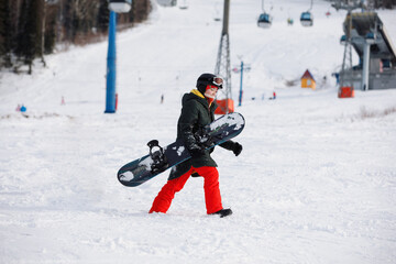 Woman snowboarder walks on the snowy mountain