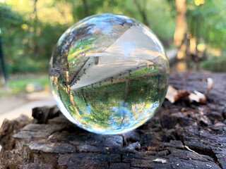 Inverted wood path seen through glass ball on wood table in early morning