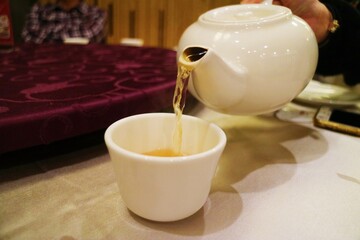 Someone picks up a white teapot and is pouring tea
