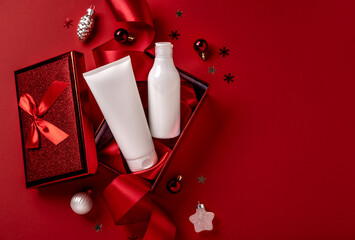 White bottles cosmetic products in red giftbox and on red background. Christmas sale of beauty...