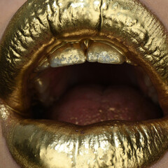 Obraz premium Gold paint on lips. Golden lips, sensual woman mouth. Metallic creative art make up close up. Gold concept. Golden art design.