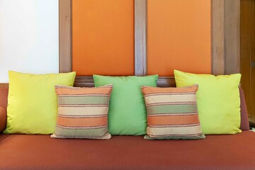 Green and brown cushions on a brown fabric long sofa in a modern home living room
