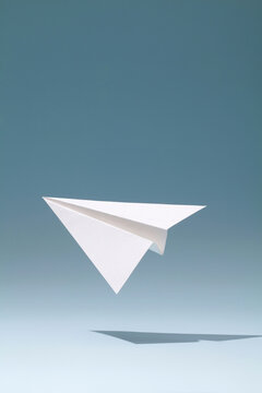 photo of white paper plane on blue background.