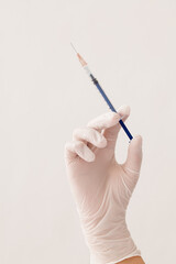 a hand with glove holding an injection needle on white background.
