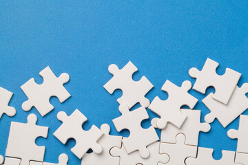 scattered white jigsaw puzzle pieces on blue background.