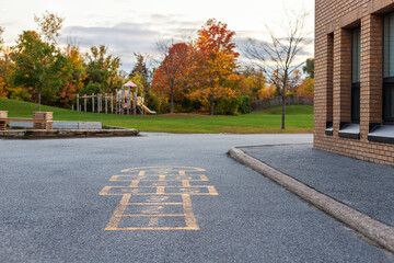 School building and schoolyard with playground for children in evening in fall season. Selective...