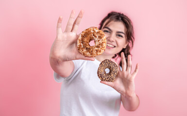 Portrait of a pretty, young woman showing donuts isolated over pink background.