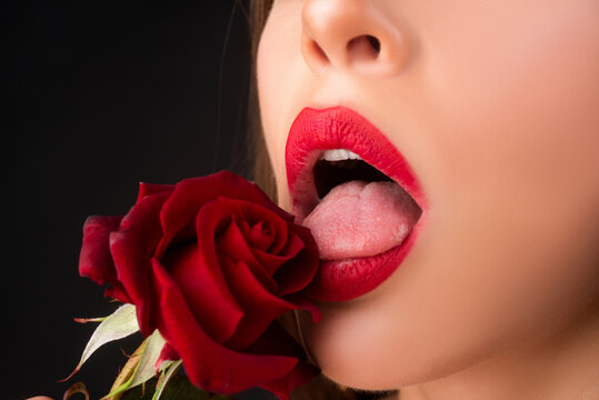 Lips with lipstick closeup. Beautiful woman lips with rose. Woman with red rose, macro, on black background.