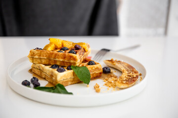 Close-up of Belgian waffles with berries and fruits.
