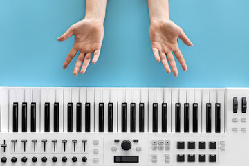 Female hands and musical keys on a blue background, top view.