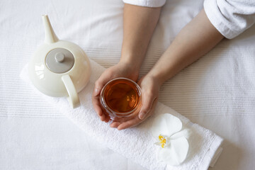 Spa composition with a cup of tea in female hands, an orchid and a teapot. © puhimec