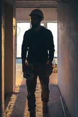 A man builder in work clothes with a protective helmet at a construction site.