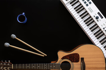 Musical background with guitar, piano, drum sticks and a cup of coffee.