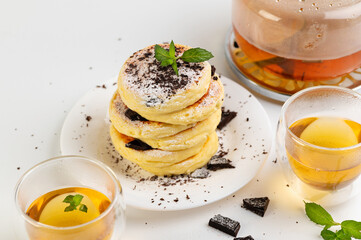 curd cakes, curds on a white dessert plate with chocolate and mint, green tea in glass cups