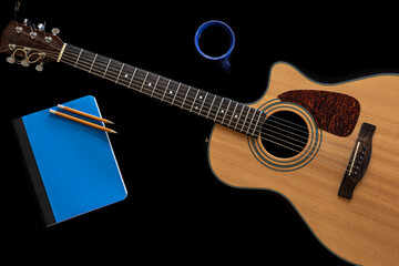 Classical acoustic guitar, notepad and a cup of coffee on a black background.