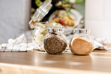 Spices in glass jars on the kitchen table in the kitchen. Copy space