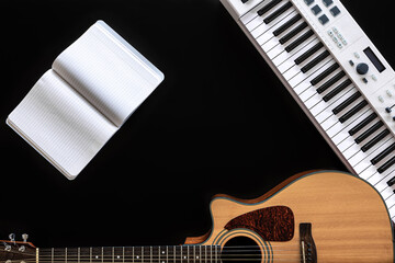 Music background with acoustic guitar, notepad and music keys on black.