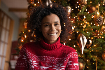 Close up portrait of smiling young biracial woman celebrate Christmas holidays at home talk on...