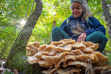 Female mushroom picker foraging for mushrooms in the forest