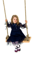 Lovely blonde little girl swinging on rope swing
