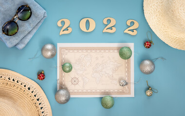 Travel flat lay composition with world map and numbers 2022 on blue background.