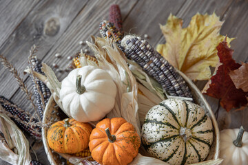 Autumn composition with pumpkins, corn and leaves on a wooden background.