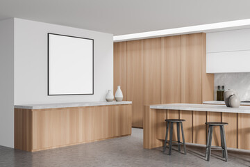 Empty frame on white wall in modern minimalist wood kitchen. Corner view.