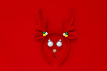 Santa deer antlers. eyes with Christmas toys mouth made from red paper clips. Minimalist concept of Christmas. Creative winter pattern.