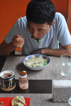 A asian guy eating thenthuk (tibetan cousin) in fast food cafe