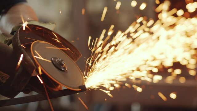 Close up shot of unrecognizable worker using electric cutting wheel making sparks while cutting metal
