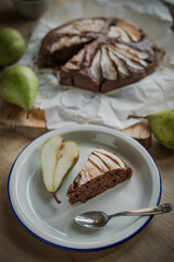 Rustical chocolate cake with pear, traditional winter and autumn desert with seasonal fruit, homemade pastry, served on the plate powdered with cocoa