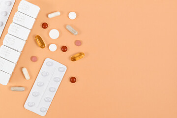 Medical pills, capsules and pill box on side of orange background with copy space