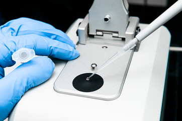 Scientist pipettes sample onto the low pedestal of Nanodrop for measuring the concentration of...