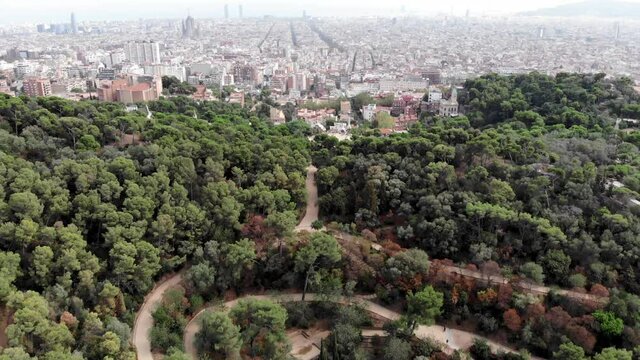 Drone shot from Park Guell in Barcelona. Panoramic view of the city of Barcelona. Spain from drone. Park at the top of Barcelona. Drone view of gardens and residential areas in Spain.