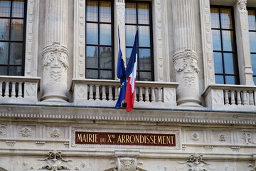 Façade en pierre de la mairie du dixième arrondissement.  Avec drapeaux français et européen....