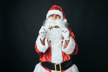 Man dressed as Santa Claus holding a star, on black background. Concept of Christmas, Santa Claus, gifts, celebration.
