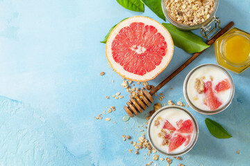 Vegan healthy breakfast. Granola with greek yogurt, honey and grapefruit in a glass. Top view flat lay background. Copy space.