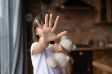 Scared little girl making no sign, showing hand stop gesture at camera. Open palm, outstretched arm...