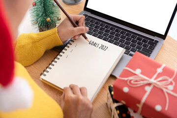 Woman hand writing New year's goals on note paper in new year day.