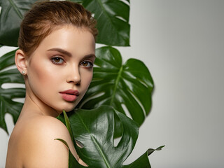 Beautiful woman with green leave near face and body. Closeup girl's face with green leave. Pretty...